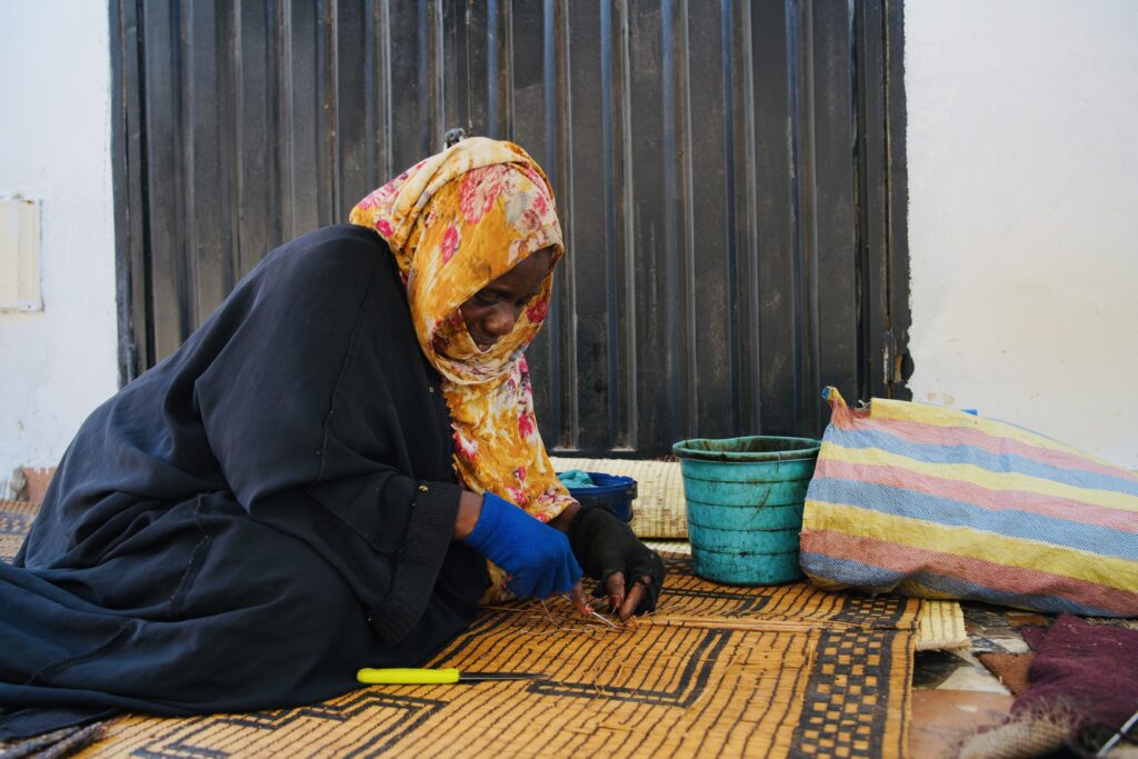 artisane africaine tissant une nappe à la main